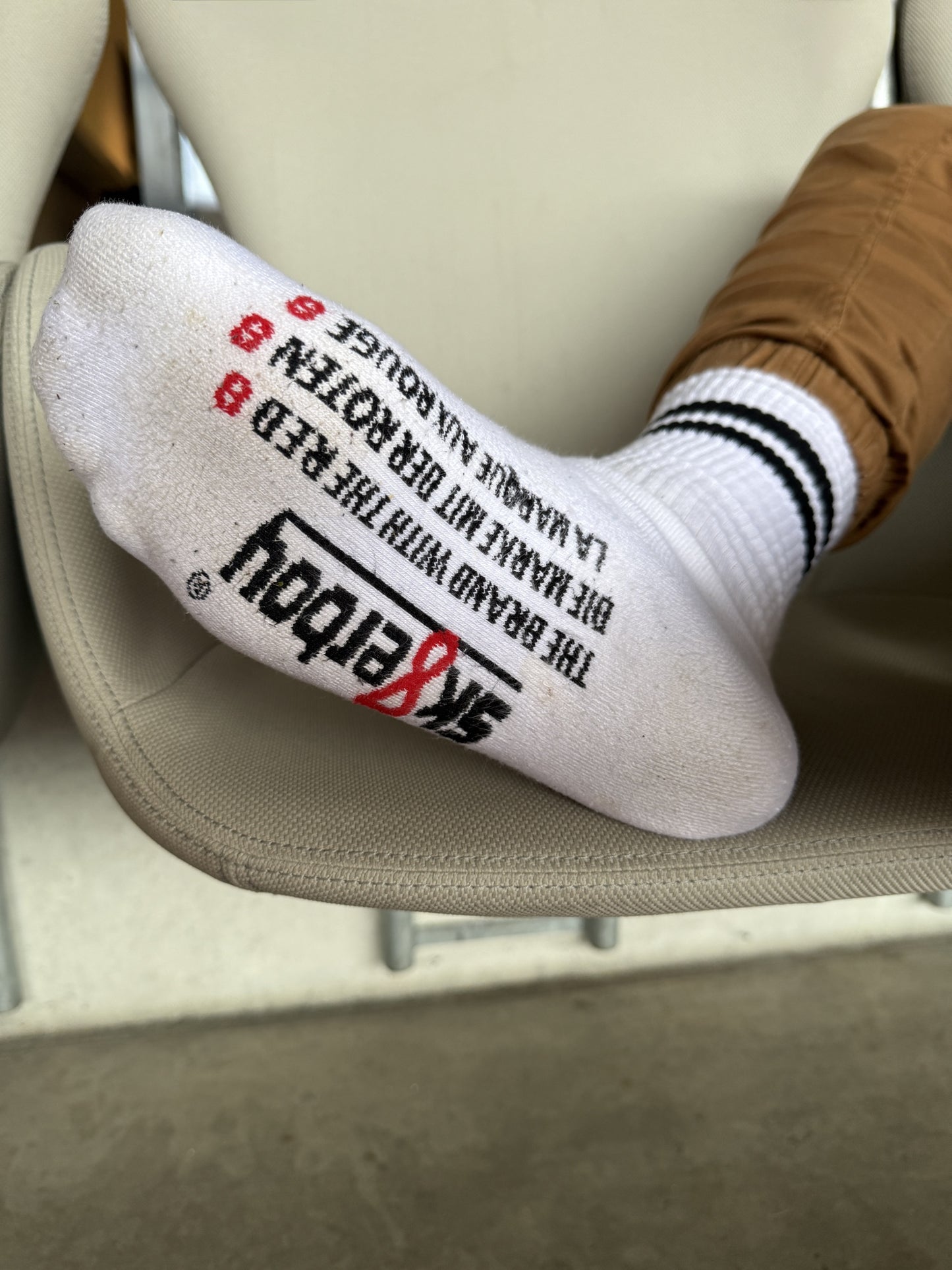 Lässiger Stadion-Moment: Sk8erboy® Retro Socken mit schwarzen Streifen und auffälligem Print auf der Sohle, kombiniert mit weißen Nike Air Force 1 – stylischer Streetwear-Look mit Attitude.