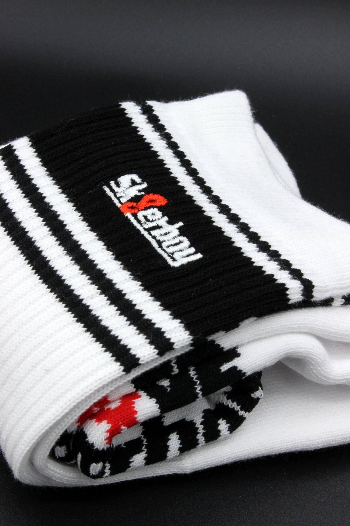 detailansicht der sk8erboy deluxe socken in schwarz mit schwarzem streifen am bund und sk8erboy logo auf der extra flauschigen unterseite