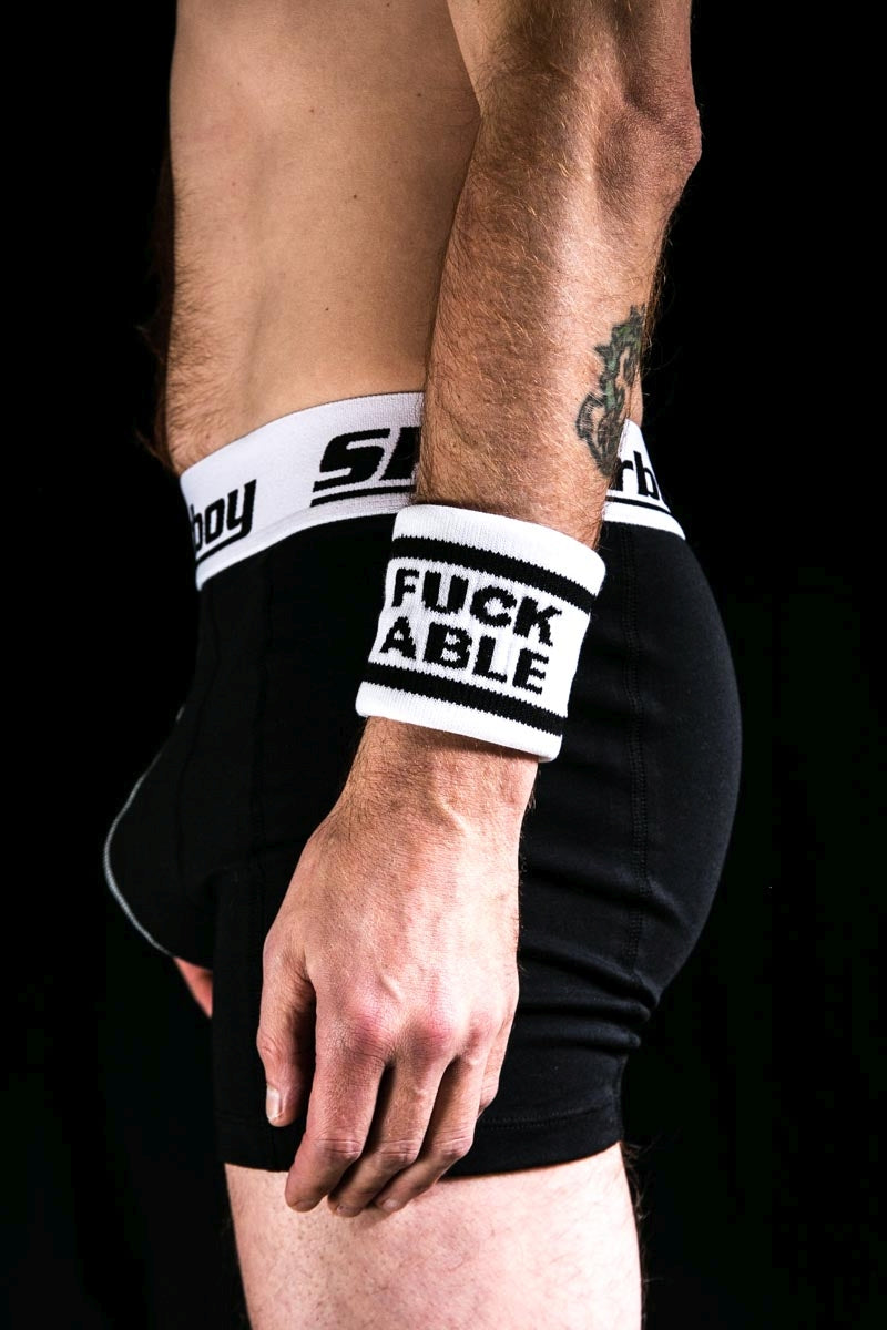 gay dans l’obscurité avec un boxer noir sk8erboy et un bandeau anti-transpiration au bras gauche avec l’inscription FUCK ABLE de sk8erboy socken shop