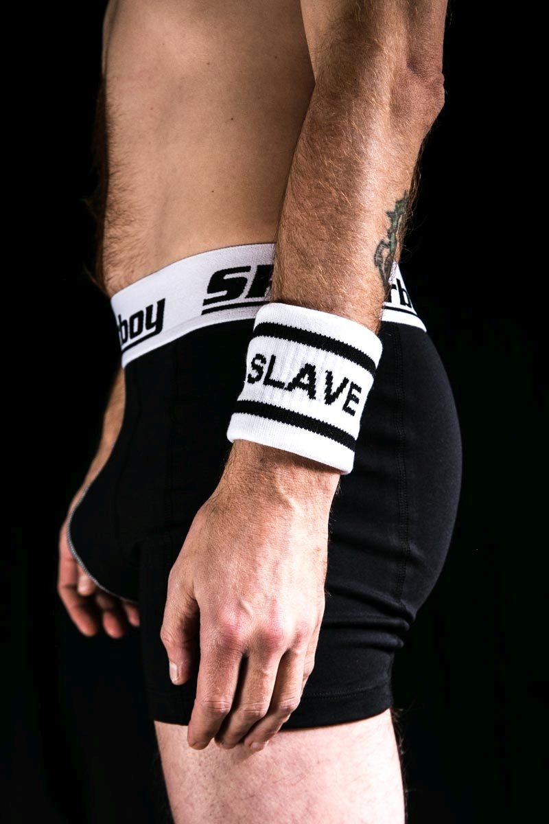 gay dans le noir avec un boxer noir Sk8erboy et un bracelet éponge au bras gauche avec l’inscription SLAVE de sk8erboy socken shop pride arc-en-ciel lgbt