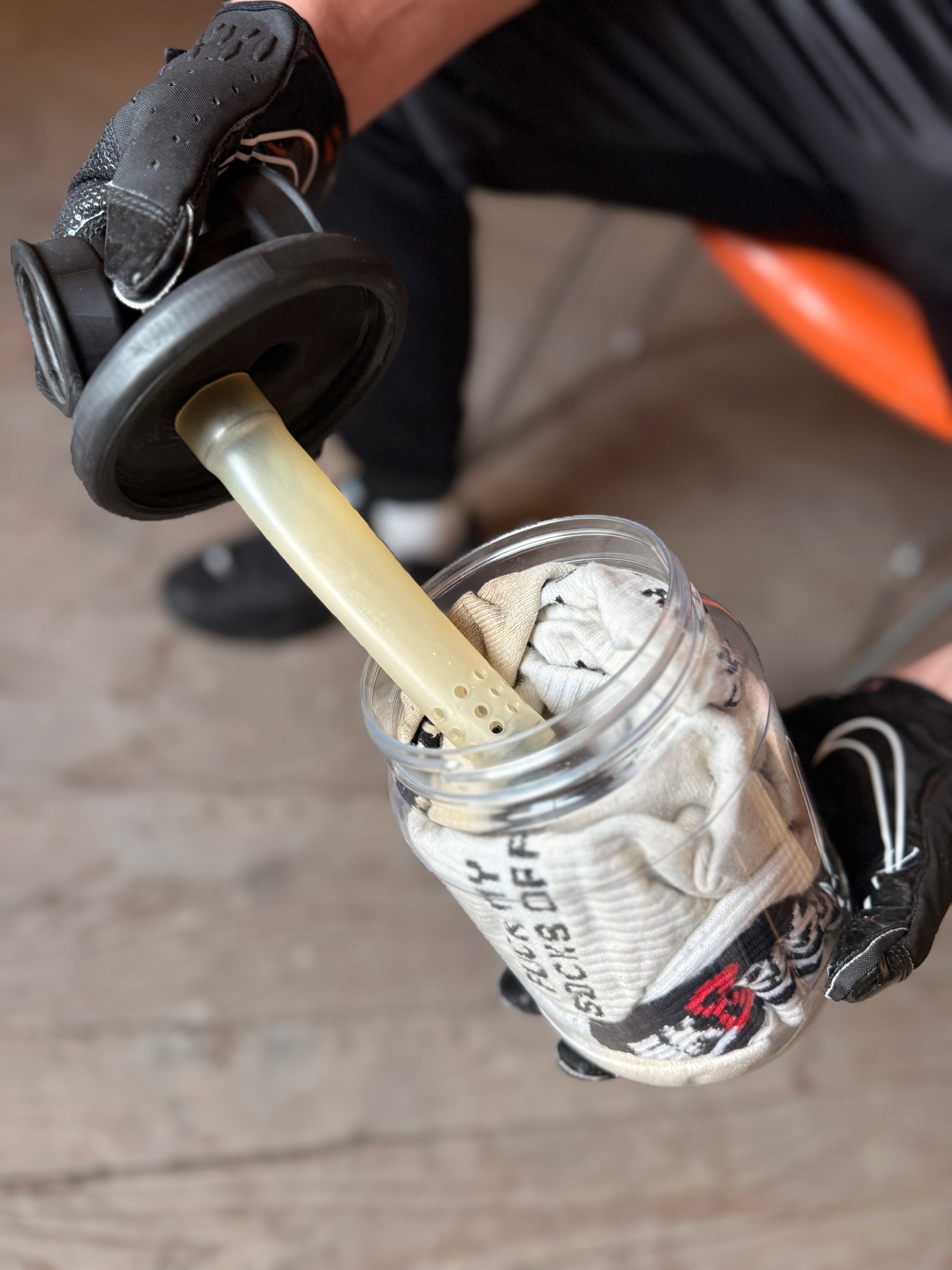 Sk8erboy Vast Sniffer Glas wird geöffnet, schwarze Handschuhe halten den Deckel mit Filtereinsatz über den gefüllten Socken.