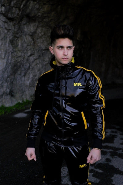 MR Riegillio PVC Tracksuit jacke mit gelben streifen von einem jungen gay getragen in schwarz glänzend mit passender hose von vorne