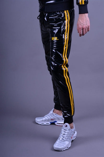 MR Riegillio PVC Tracksuit Hose mit gelben streifen von einem jungen gay getragen in schwarz glänzend mit weissen nike tn sneakern von der seite