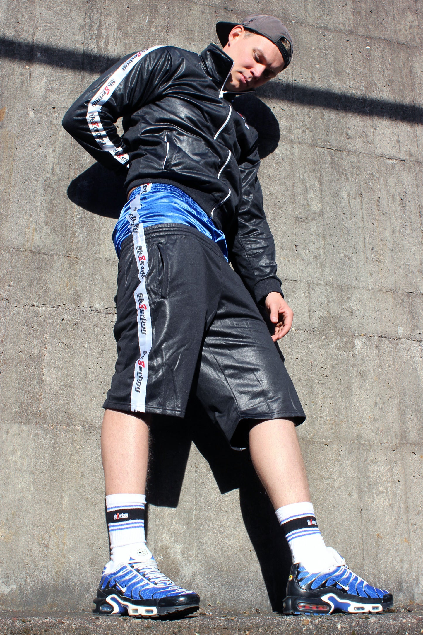 sk8erboy shiny Glanz glaenzende boxershort in royalblau blue mit fettem sk8erboy satin streifen an der Seite der boy Kerl Bengel toy traegt noch das komplette shiny sk8erboy outfit mit Jacke und short seine drolligen deluxe socks auch in royalblau smellen fett aus den nike tn tuned air max plus raus in einem stylischen Sammlerfarbton er kniet auf beton