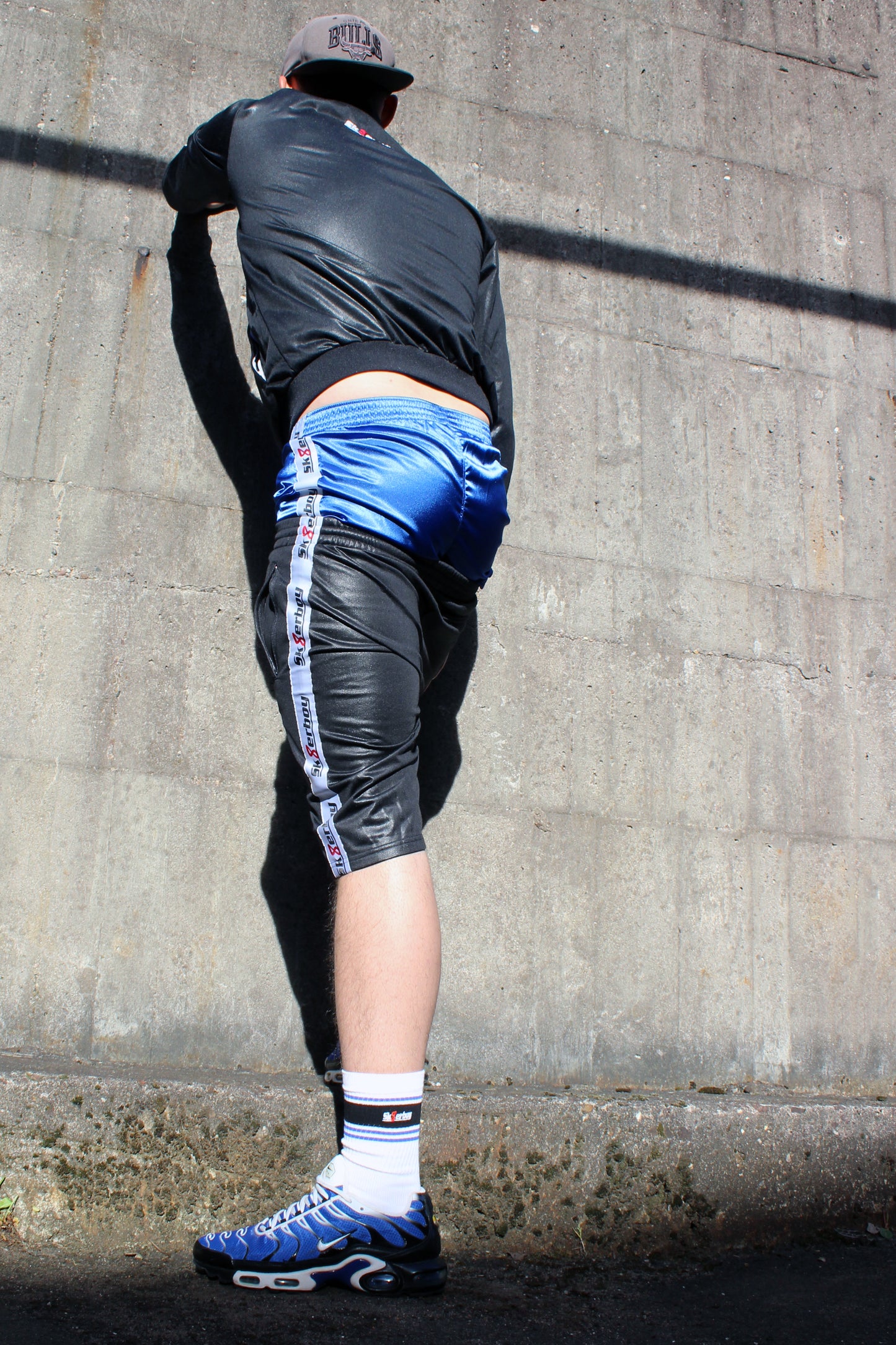 sk8erboy shiny Glanz glaenzende boxershort in royalblau blue mit fettem sk8erboy satin streifen an der Seite der boy Kerl Bengel toy traegt noch das komplette shiny sk8erboy outfit mit Jacke und short seine drolligen deluxe socks auch in royalblau smellen fett aus den nike tn tuned air max plus raus in einem stylischen Sammlerfarbton er kniet auf beton