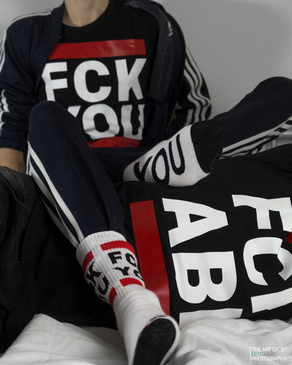 zwei gays auf dem bett in sportklamotten von adidas mit sk8erboy socken fck you und passendem t-shirt in schwarz