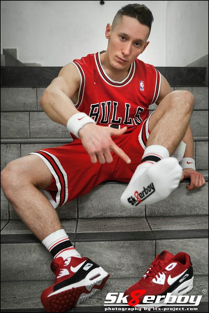junger sportlicher typ sitzt auf einer treppe mit chicago bulls tank top passend zu seinen nike air max sneaker in rot und sk8erboy deluxe socks in rot