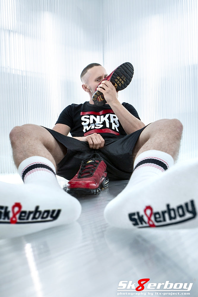 junger gay auf dem boden in sportklamotten greift sich in den schritt und traegt sk8erboy deluxe socks in rot mit passenden nike tn sneaker in rot