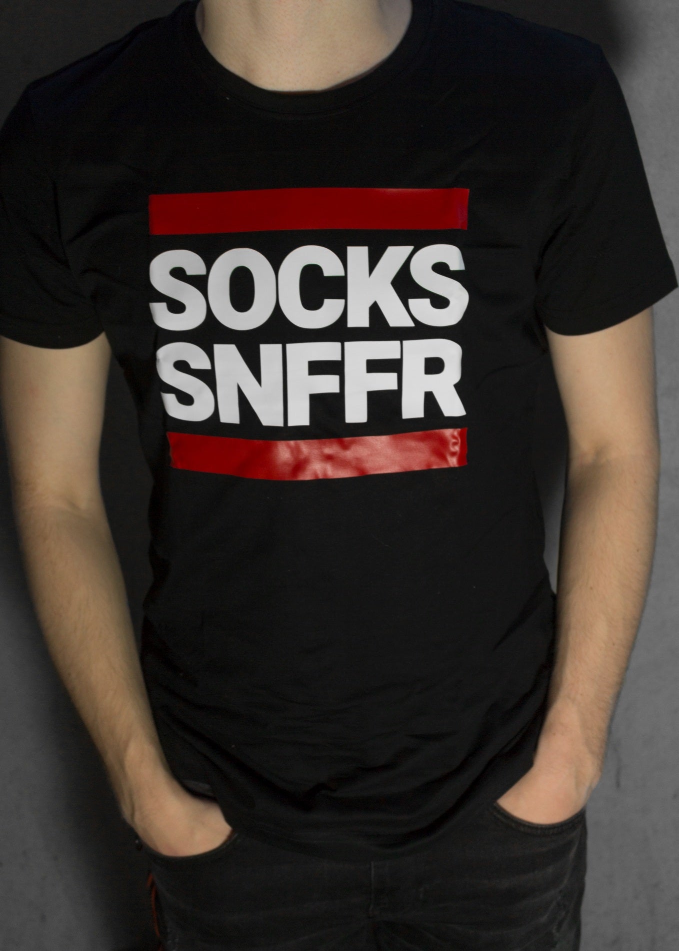 junge mit schwarzen t-shirt mit dem aufdruck socks snffr in weissen buchstaben mit roten balken