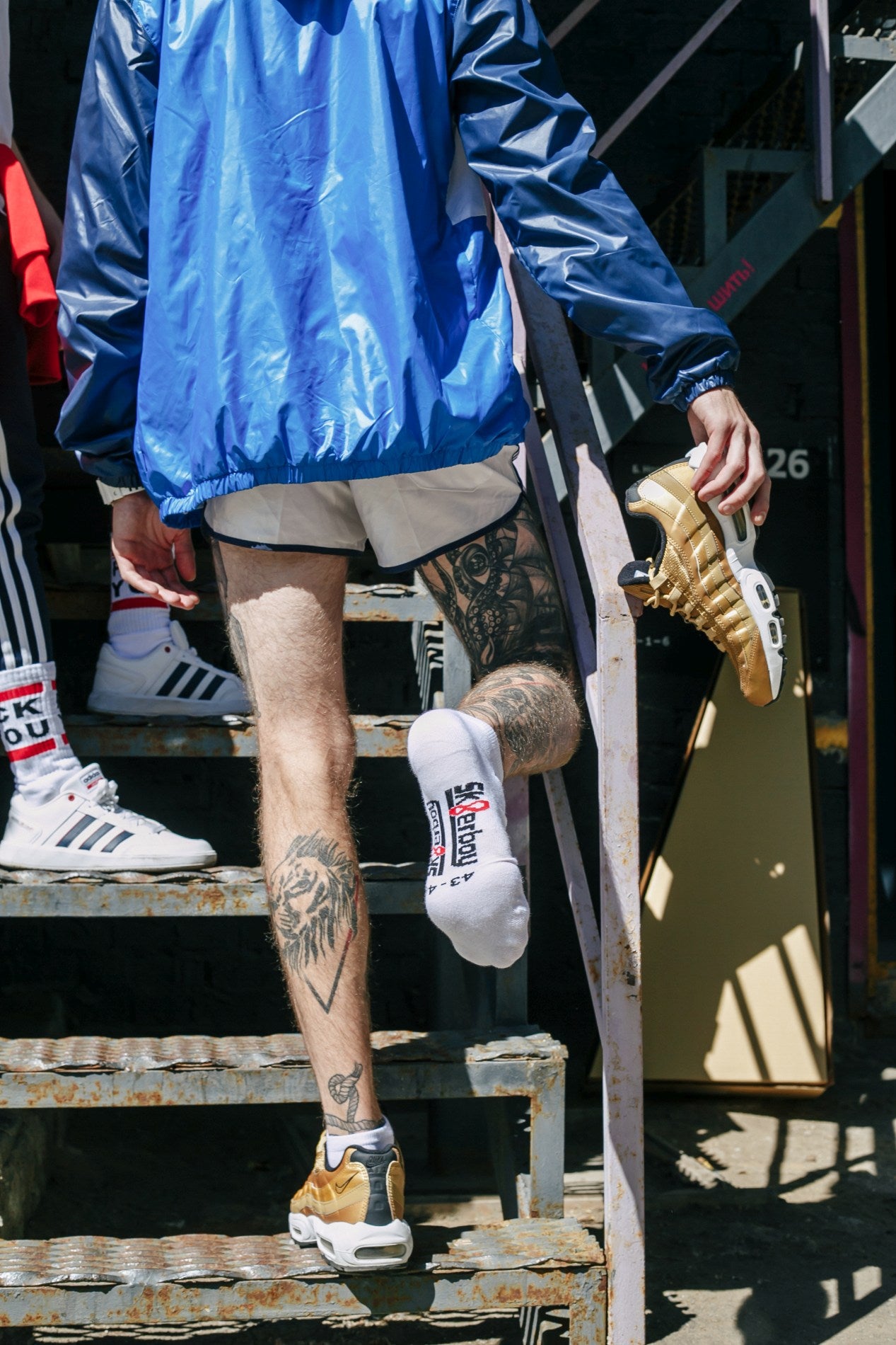 gay mit tattoo von hinten auf einer treppe mit weissen sneaker socks von sk8erboy und fck you socks in nike und adidas sneakern