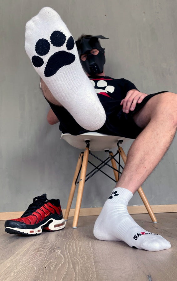 junger gay doggy traegt weisse sk8erboy puppy short crew socks mit hunde pfoten in schwarz und dog paw t-shirt mit hundemaske zu seinen roten nike tn haelt einen fuss mit pfote dabei in die luft